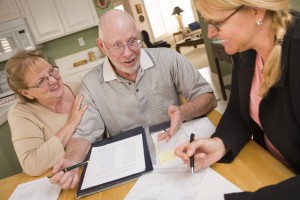 Senior Adult Couple Going Over Papers in Their Home with Agent.