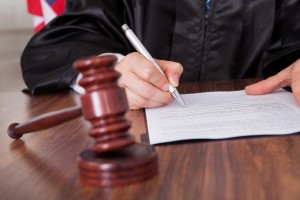 Close-up Of Male Judge Writing On Paper In Courtroom